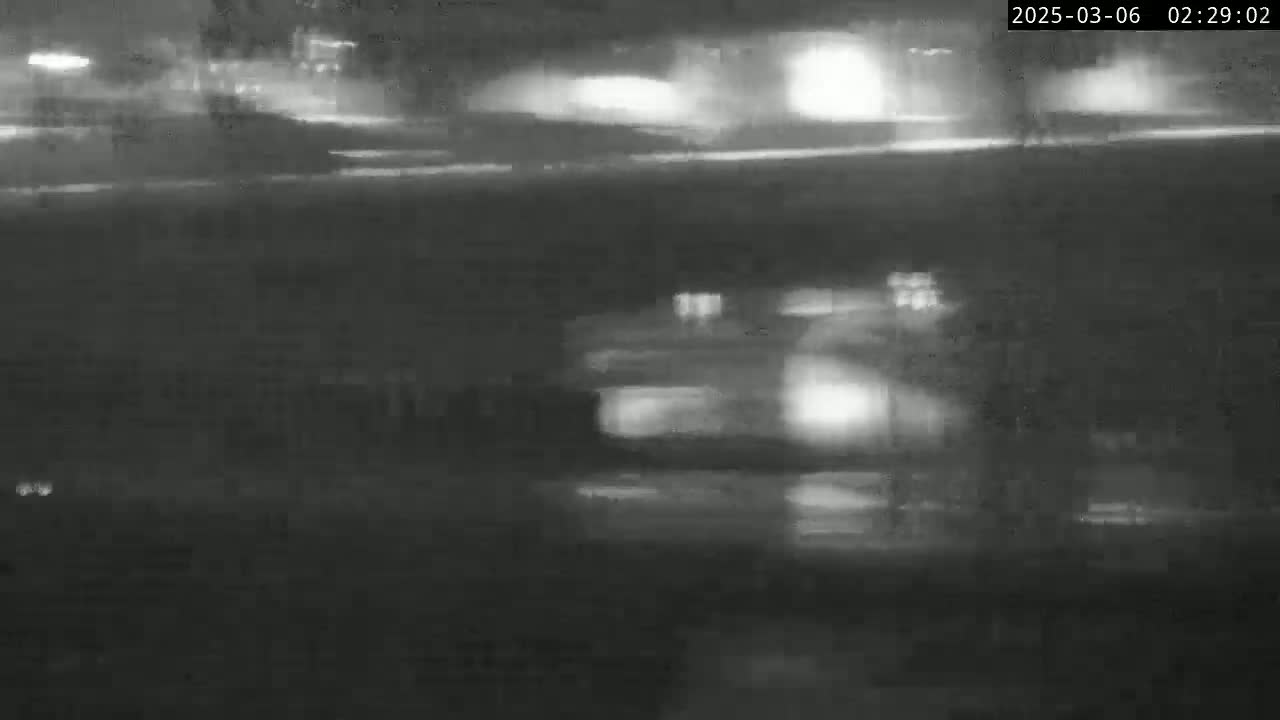A nighttime, low-light image shows blurry headlights of vehicles traveling on a road.