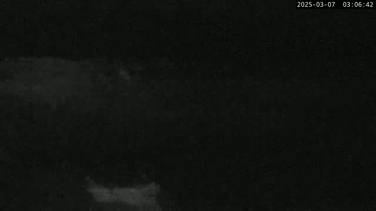 A mostly dark image shows a dimly lit, possibly overcast night scene.