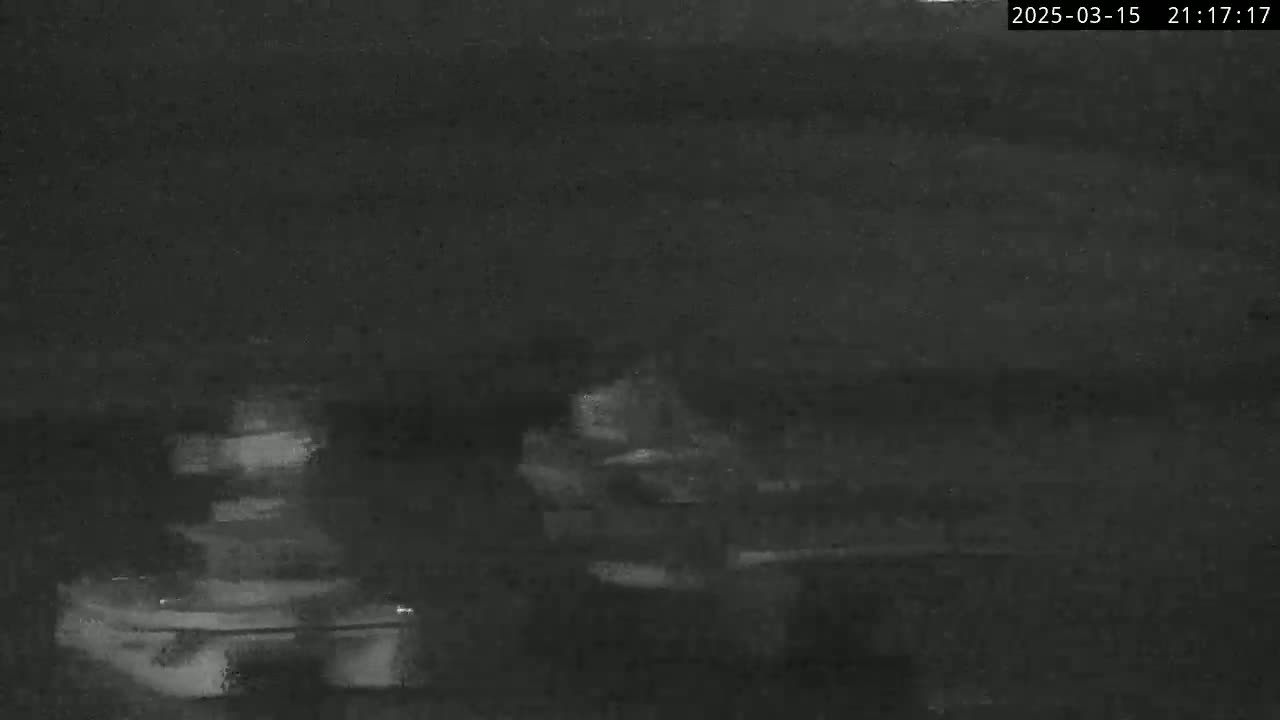 A low-light, blurry image shows two indistinct objects, possibly vehicles, on a dark surface at night.