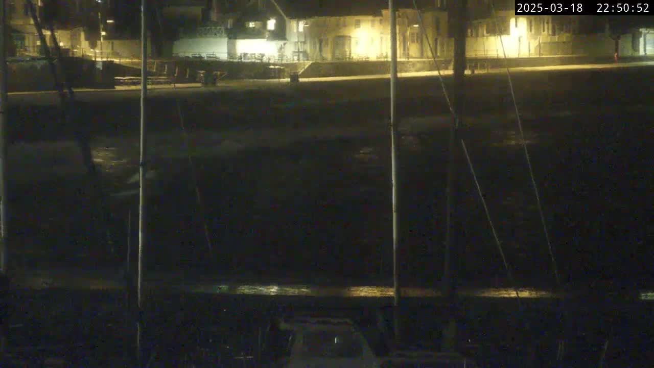 A nighttime view of a dark body of water reflecting dim lights from buildings on a shore.