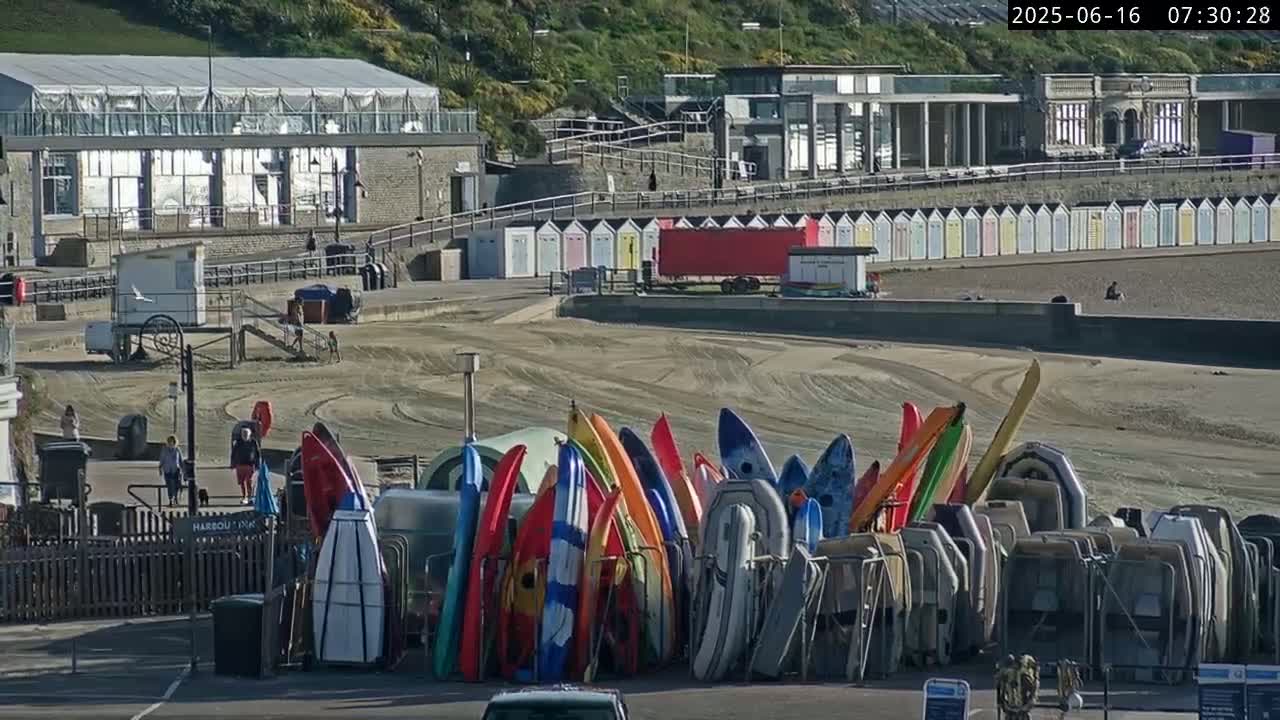 Several boats are moored in a harbor next to a building on a sunny day.