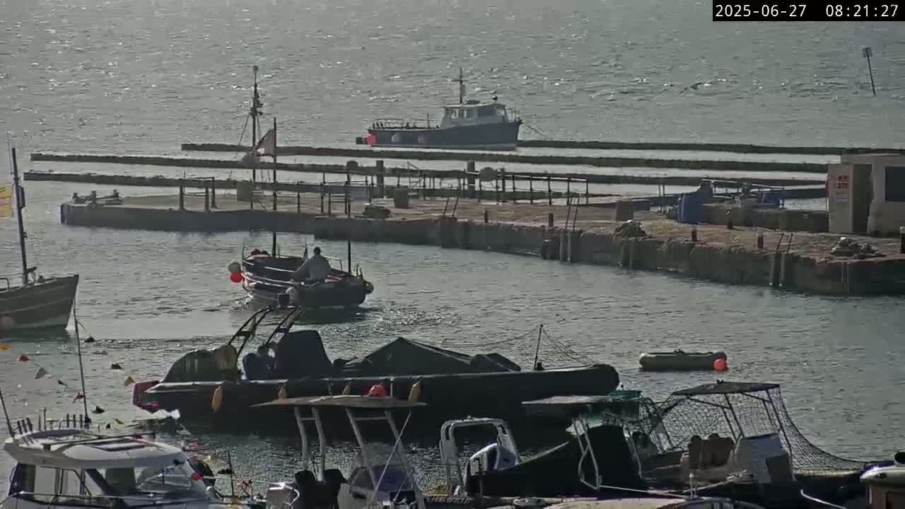Several boats are moored in a harbor on a calm, somewhat overcast day.