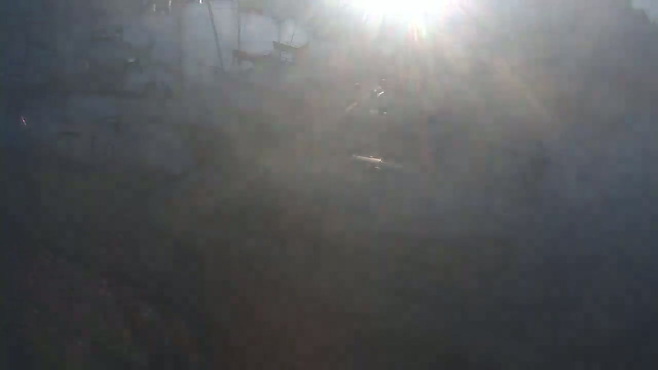 A hazy, sunlit view shows a dark, indistinct landscape with a bright light source in the upper center.