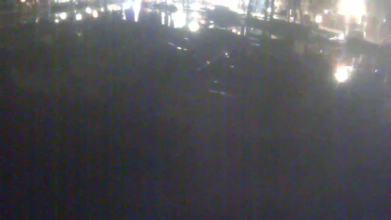 A blurry, nighttime image shows a dark, possibly paved area with indistinct shapes that might be vehicles and people.
