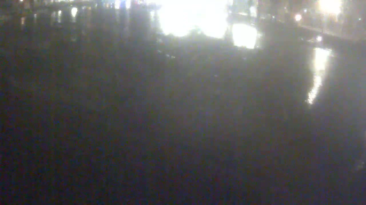 A blurry, dark image shows a wet, reflective surface at night with indistinct lights in the background.