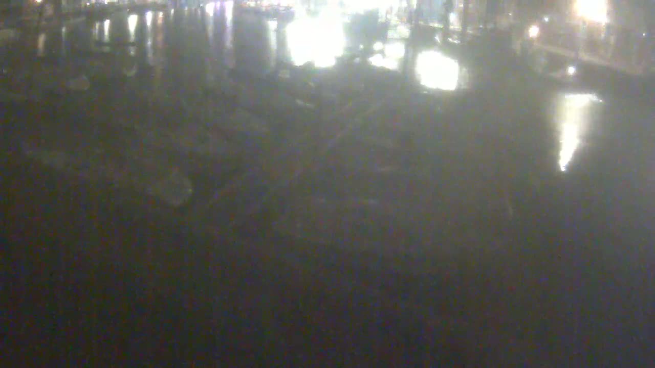 A blurry, dark image shows a wet, reflective surface at night with indistinct shapes and lights in the background.
