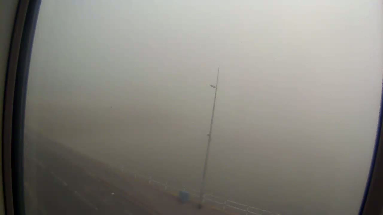A foggy view from a window shows a road and a tall pole, with vehicles barely visible in the distance.