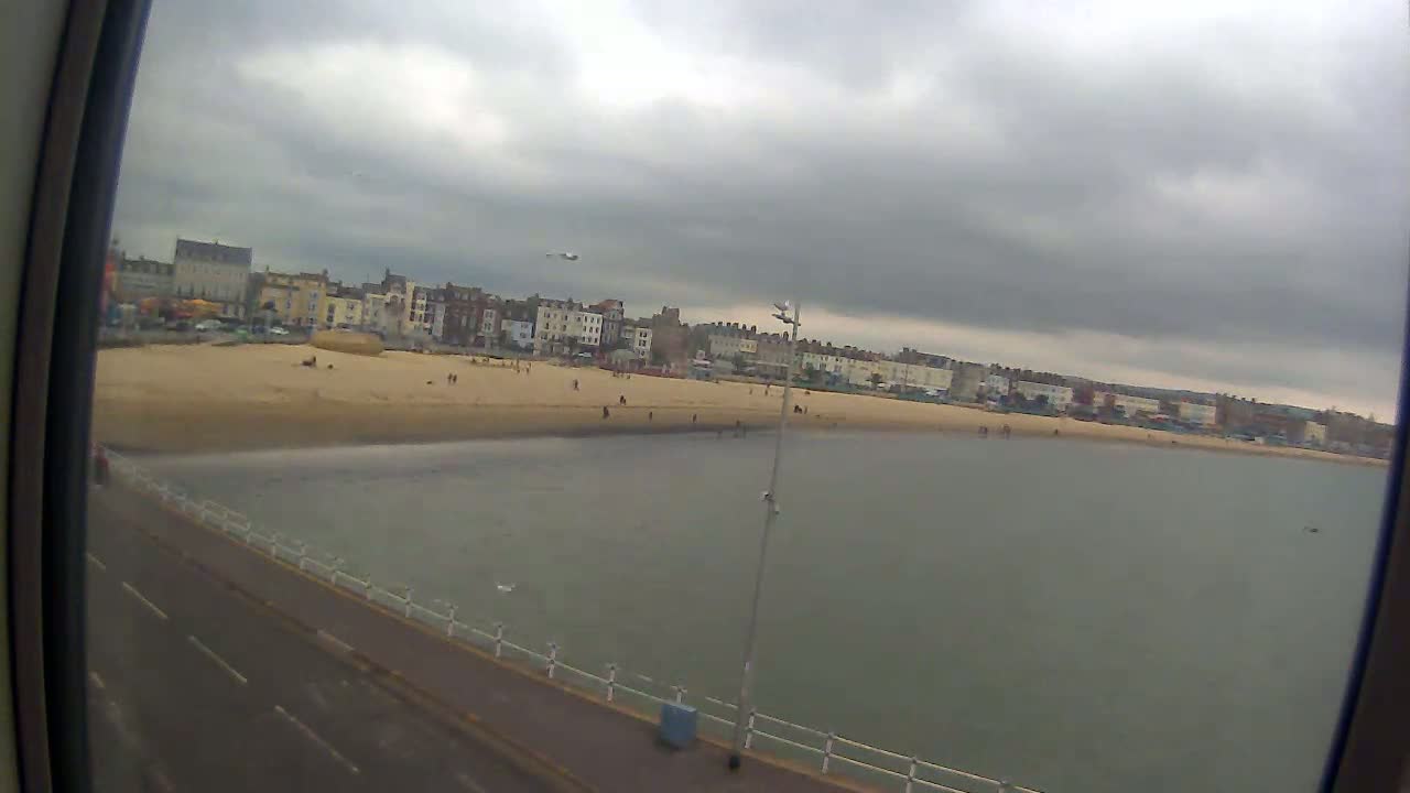A sandy beach with a row of buildings behind it is visible from a high vantage point on an overcast day.