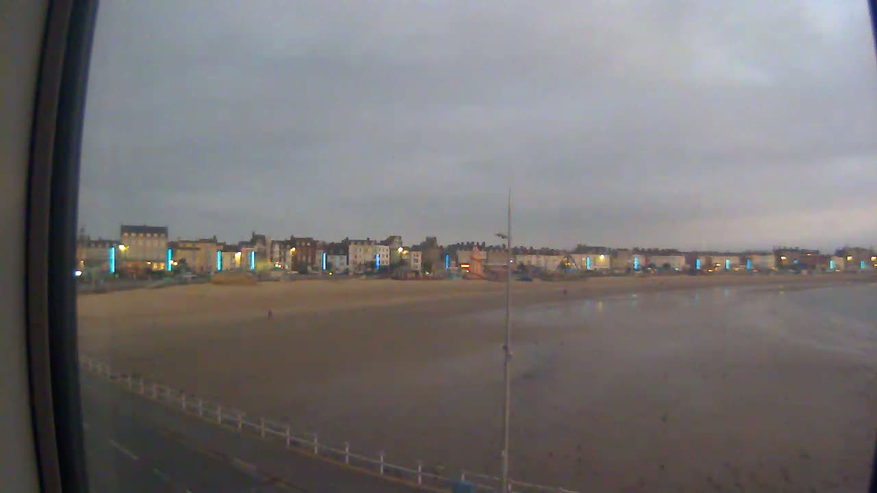 A row of buildings lines a sandy beach under a cloudy sky.