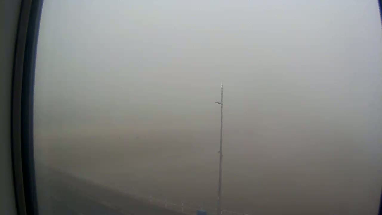 A tall pole with a light fixture is visible through a foggy, outdoor scene viewed from inside a window.