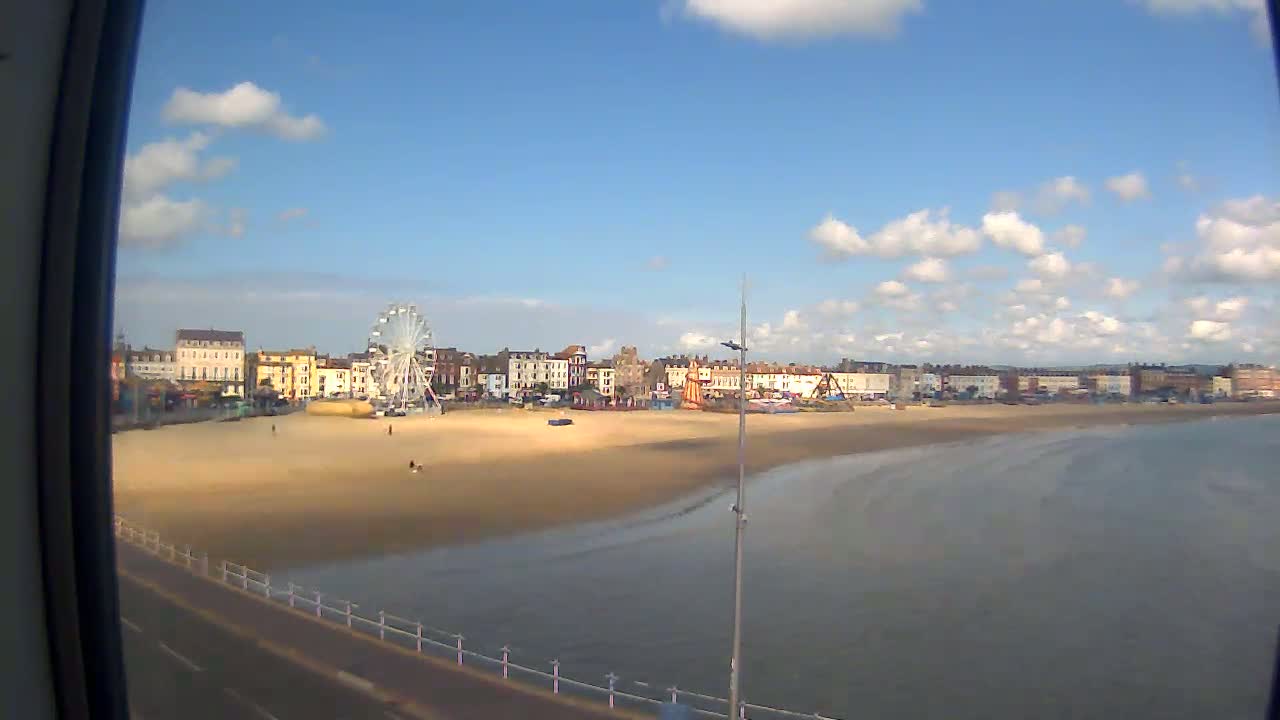 A sandy beach with a Ferris wheel and buildings behind it is visible on a partly cloudy day.