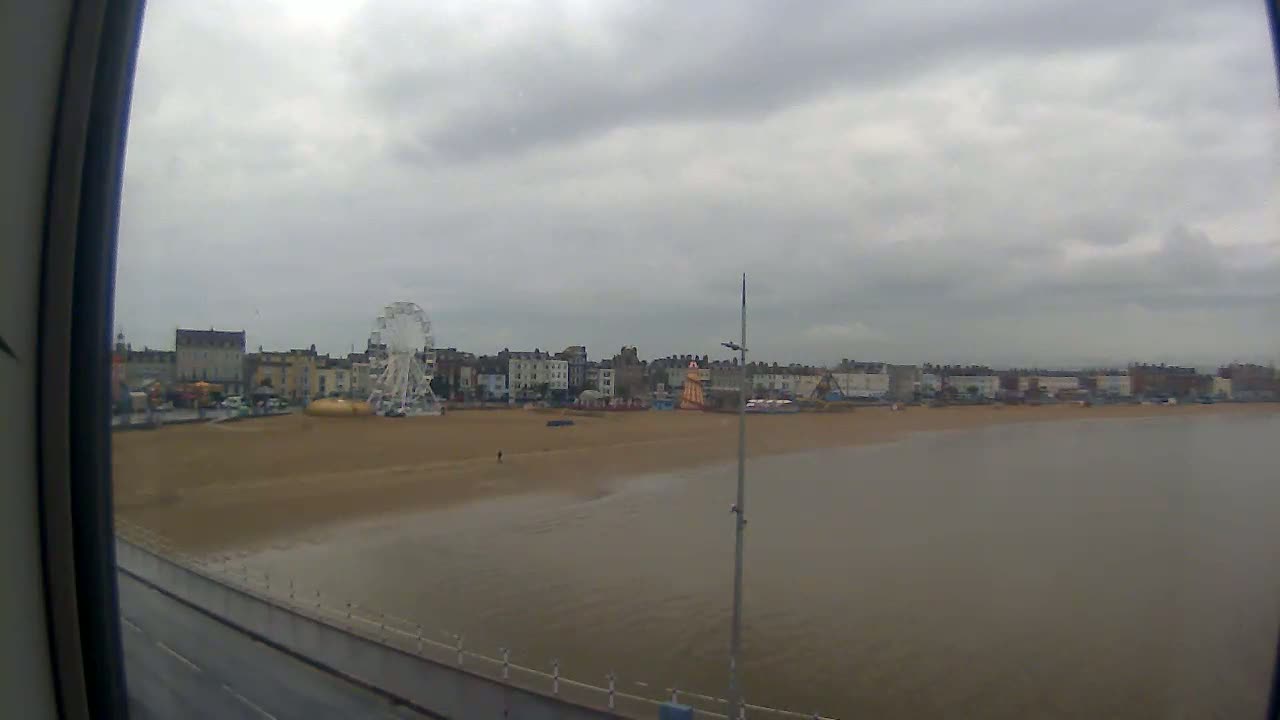 A beach with a Ferris wheel and buildings behind it is seen on an overcast day.