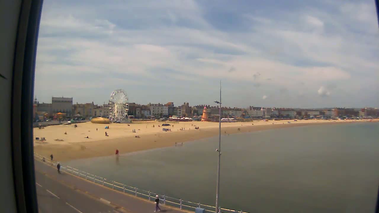 A sandy beach with a Ferris wheel and other amusement park rides is visible, under a partly cloudy sky.