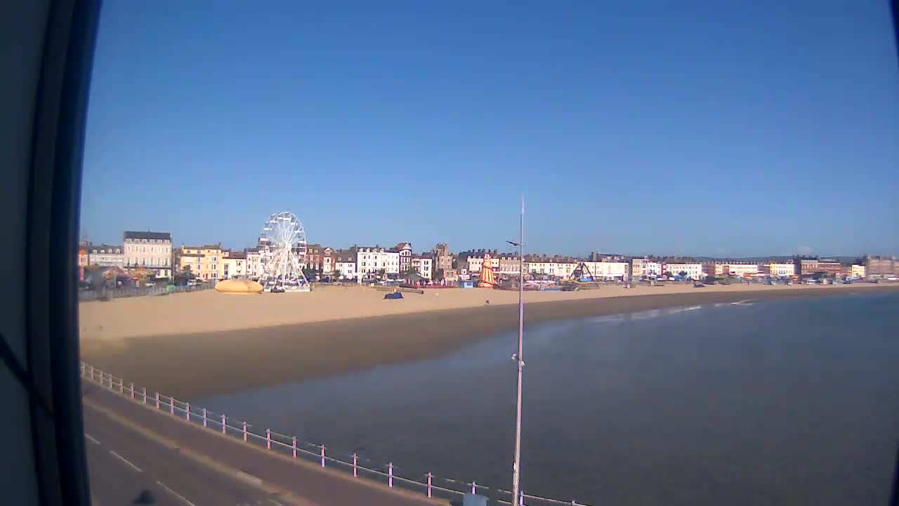A sandy beach with a Ferris wheel and buildings behind it is visible on a clear, sunny day.
