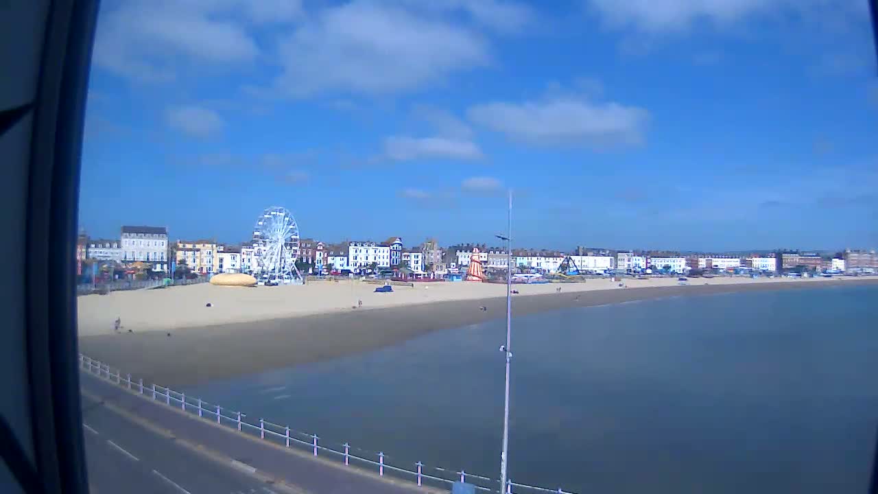 A sandy beach with a Ferris wheel and buildings behind it is visible on a partly cloudy day.