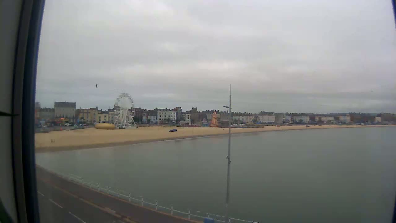 A seaside town with a Ferris wheel and sandy beach is visible on an overcast day.