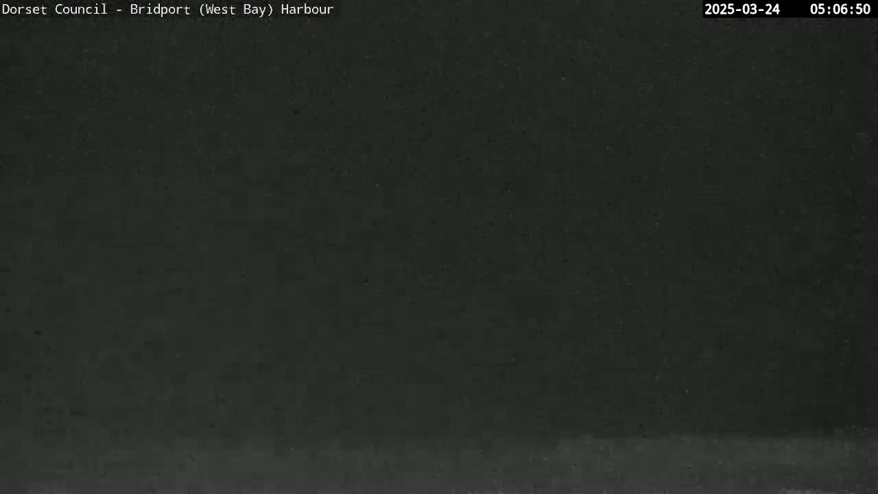 A dark, possibly nighttime image shows a mostly black scene with a very faint, lighter horizontal line near the bottom.