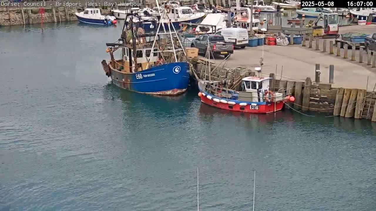 Two fishing boats are moored in a harbor on a calm day.