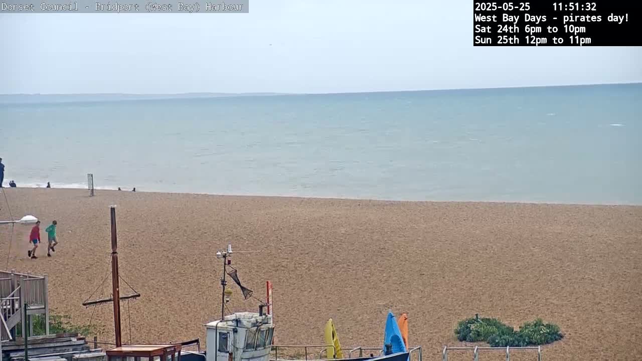 A sandy beach stretches to a calm, light-blue sea under a hazy sky.