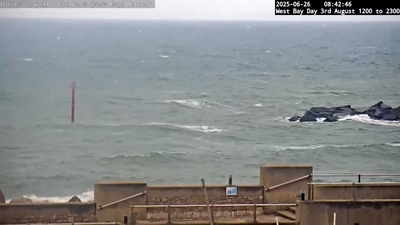 A choppy sea with small waves laps against a low stone wall.