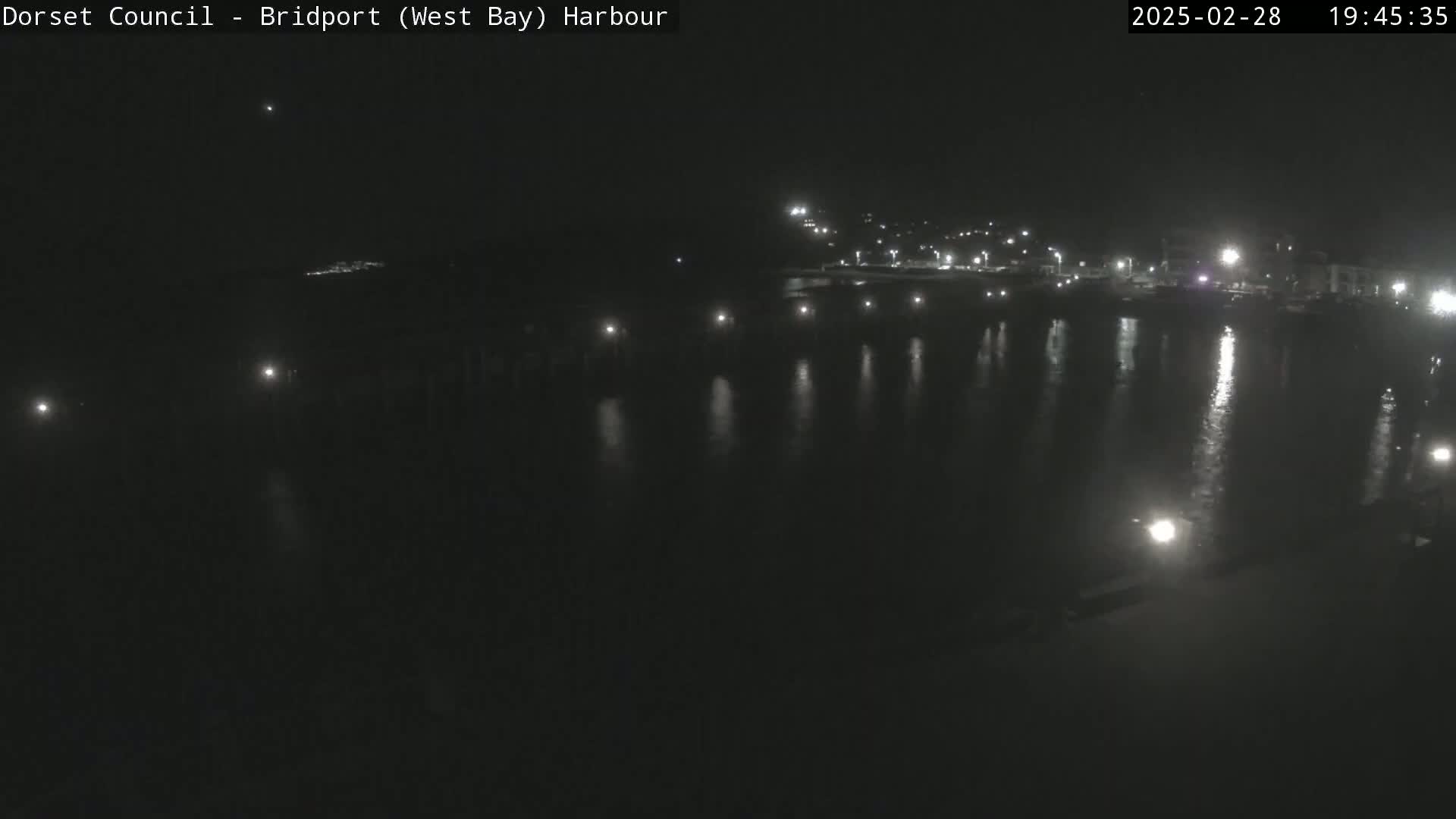 A nighttime view of a harbor with lights reflecting on calm water.
