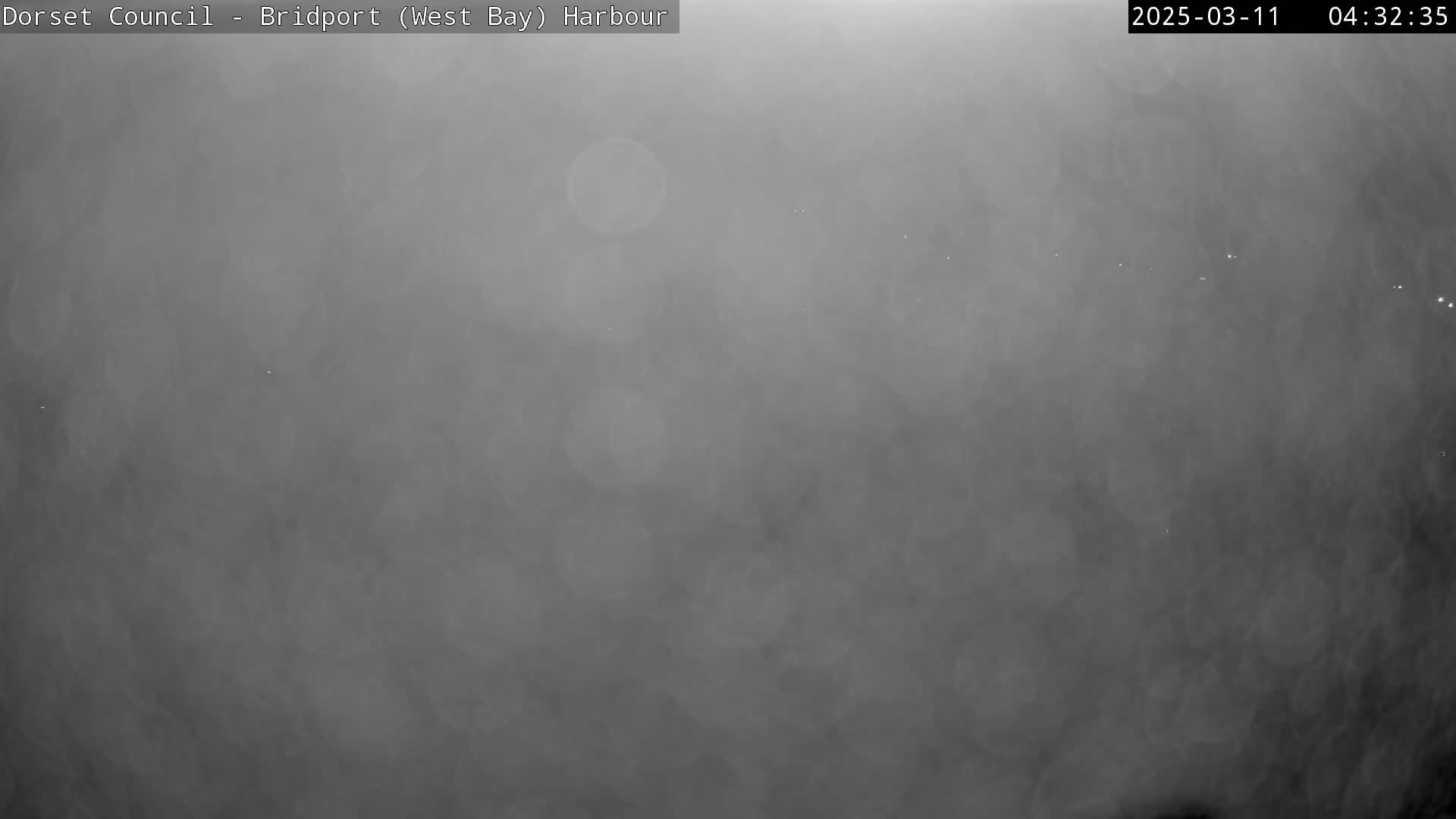 A very foggy or hazy scene is visible at night, with a few faint lights in the distance.