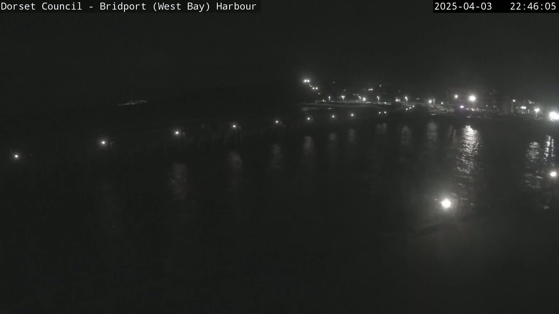 A nighttime view of a harbor with lights reflecting on calm water.