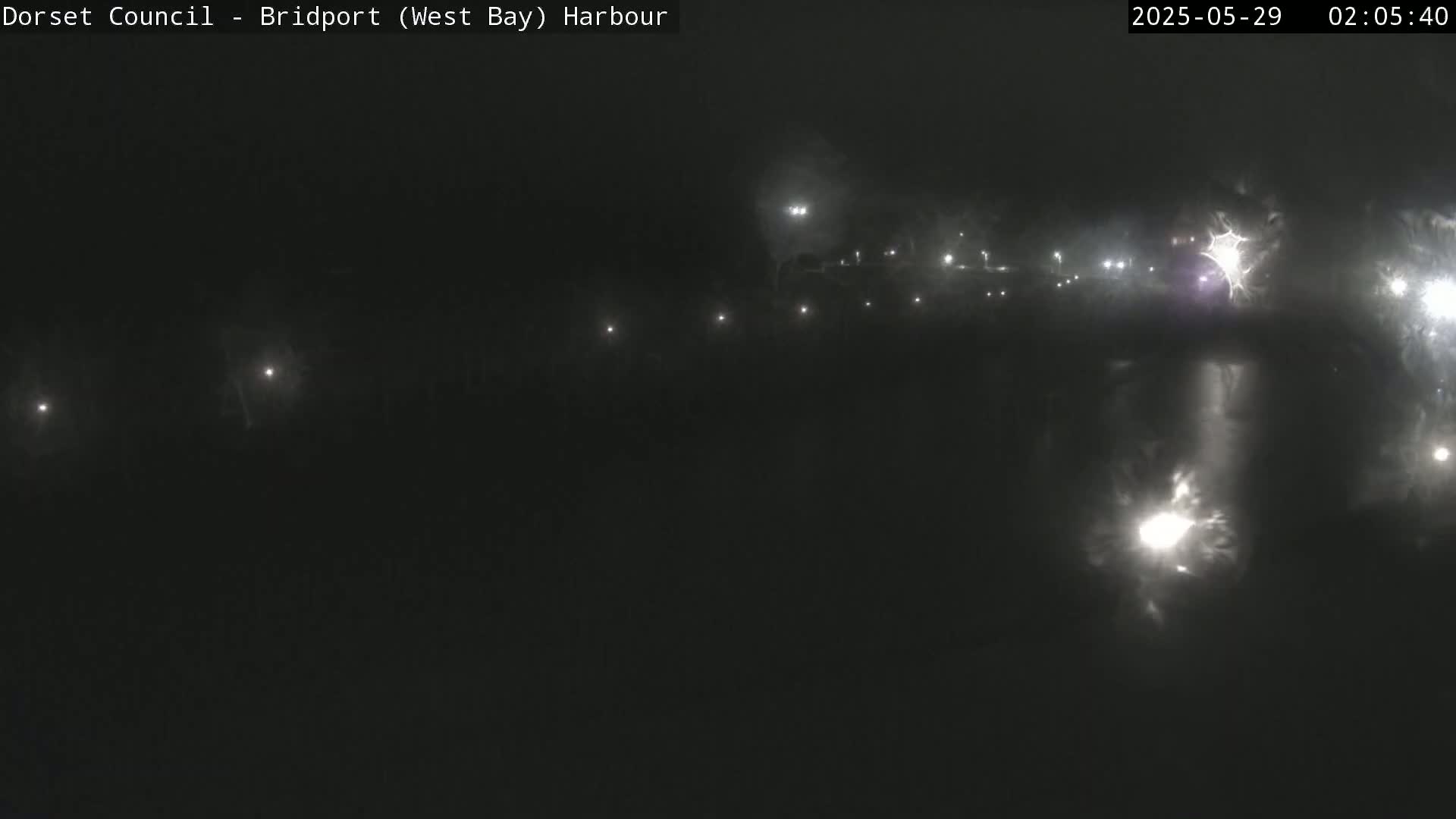 A nighttime, hazy view of a harbor with faint lights visible in the distance.