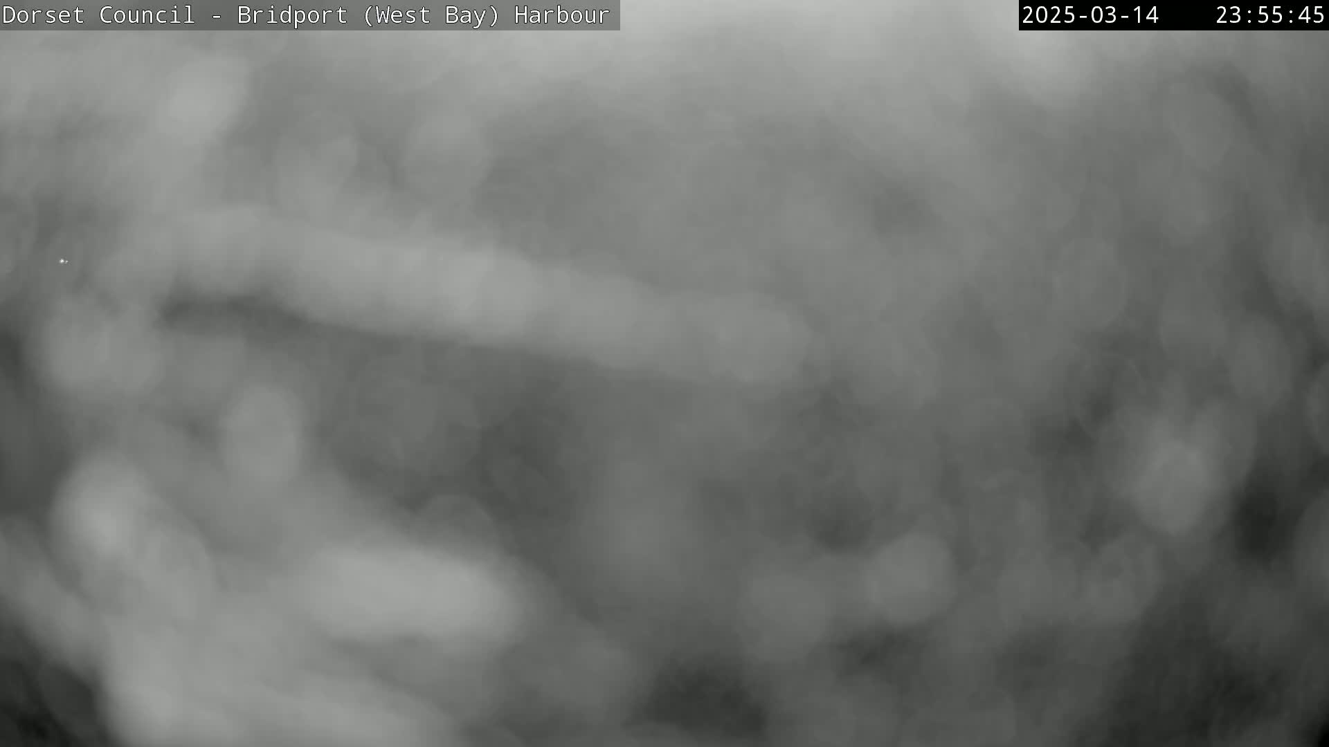 A grainy, monochrome image shows a heavily overcast sky, obscuring any view of the ground.