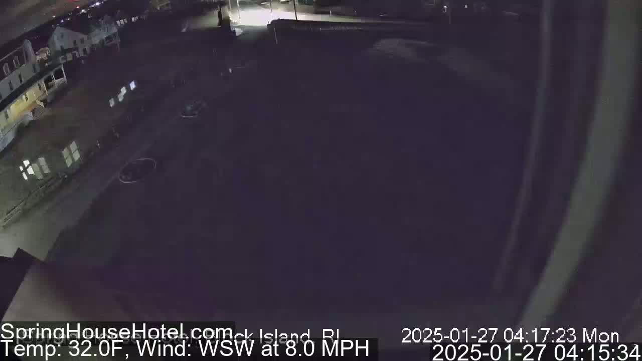 Here is a description of the image: A nighttime, wide shot of a dark parking lot and buildings, with a temperature of 32°F and a wind blowing from the west-southwest at 8 mph.