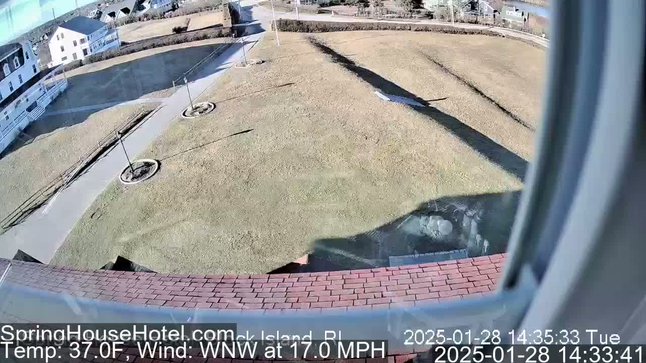 A high-angle view shows a paved walkway, grassy areas, and buildings in a sunny, windy 37°F environment.