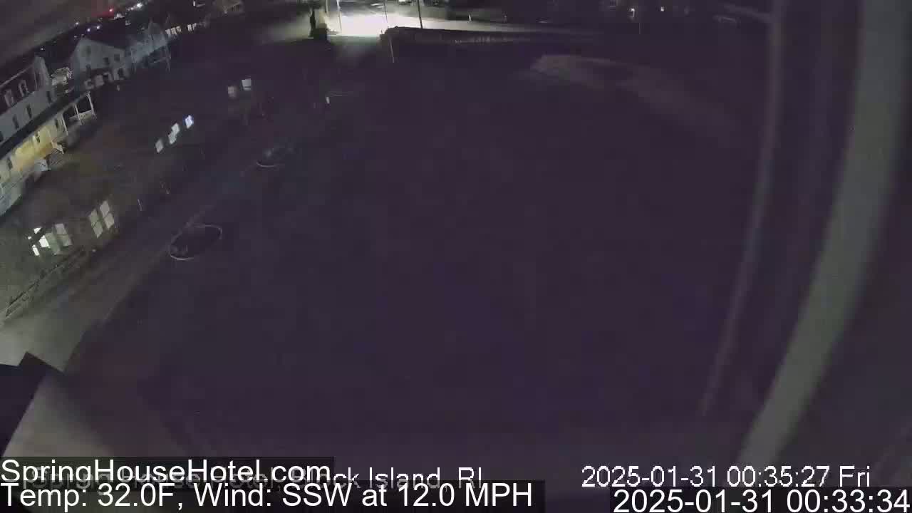 A nighttime, high-angle view of a dark parking lot and buildings under a clear sky with a 32°F temperature and a 12 mph south-southwesterly wind.