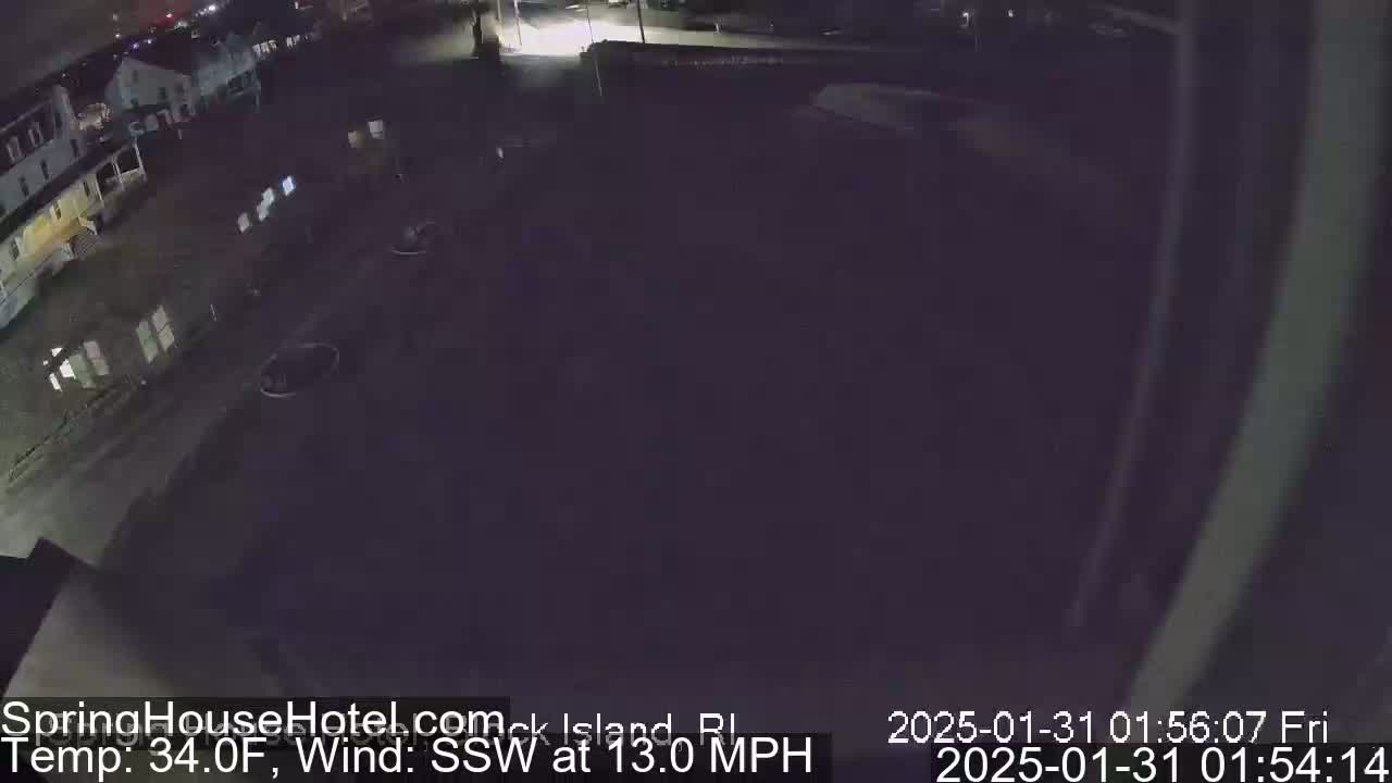 A nighttime, low-light view of a mostly empty parking lot and buildings, with a south-southwest wind at 13 miles per hour and a temperature of 34 degrees Fahrenheit.