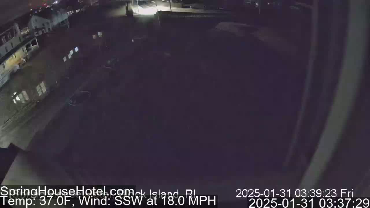 A nighttime, high-angle view of a parking lot and buildings with a 37°F temperature and 18 mph southwest wind.