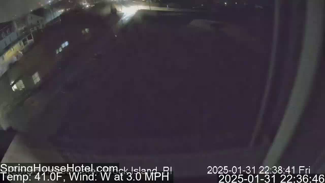 A nighttime, overhead view of a dark, mostly empty parking lot next to buildings, with a temperature of 41°F and a westerly wind of 3 mph.
