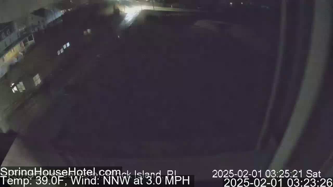 A nighttime, overhead view of a dark, mostly empty parking lot next to buildings, with a 39°F temperature and a 3.0 mph north-northwest wind.