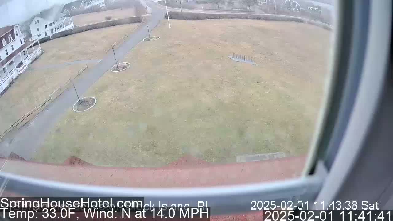 A high-angle view shows a grassy area with paths and buildings in the background, under overcast conditions with a north wind at 14 mph.