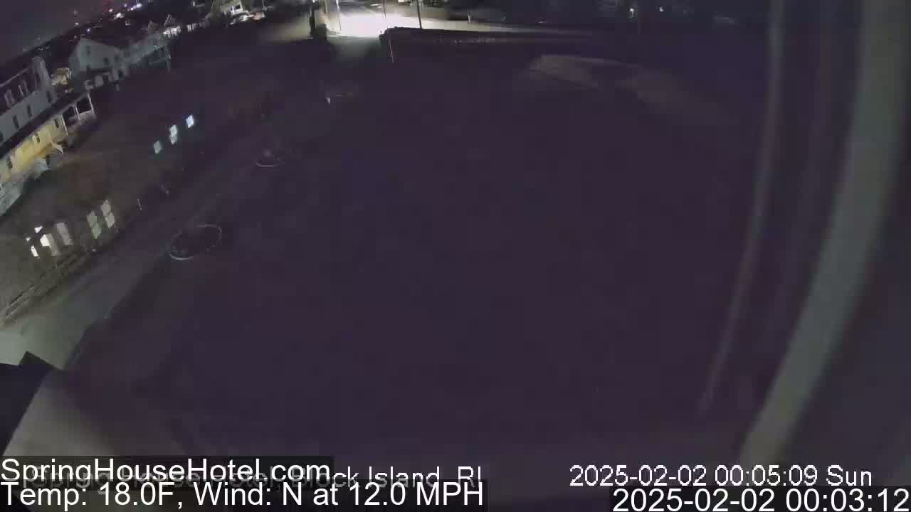 A nighttime, overhead view of a dark parking lot and buildings with a north wind at 12 mph and a temperature of 18°F.