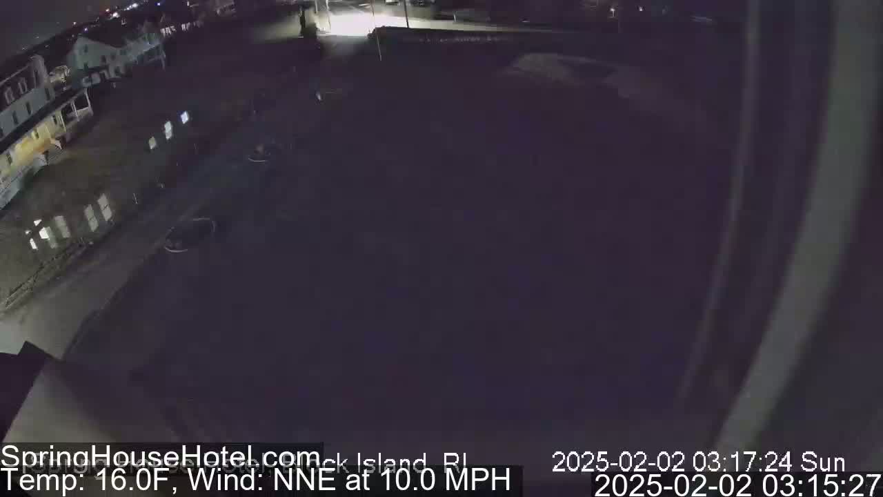 A nighttime, overhead view of a mostly empty parking lot next to a building, with a 16°F temperature and a 10 mph wind from the north-northeast.