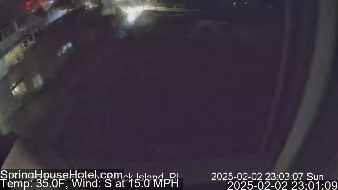 A nighttime, low-light view of a dark, mostly empty parking lot with a building visible in the upper left corner, under a dark sky with a 15 mph south wind and a temperature of 35°F.