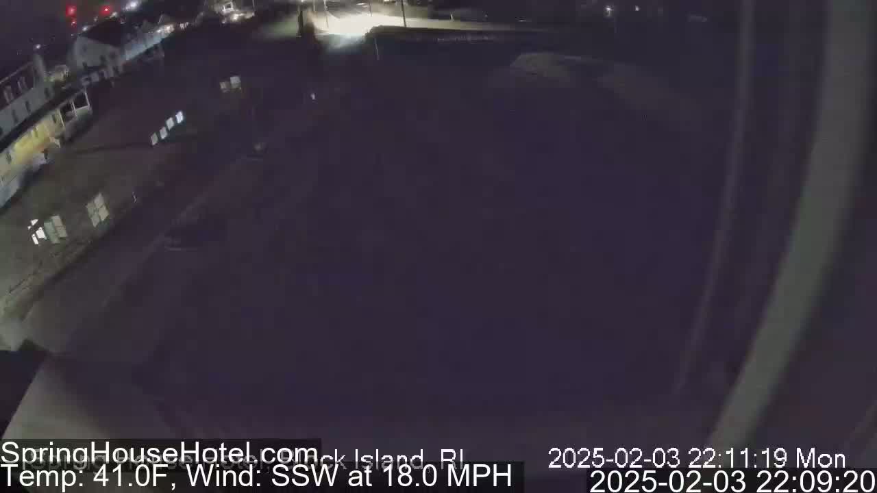 A nighttime, outdoor view of a dark street and buildings with a temperature of 41°F and a south-southwesterly wind of 18 mph.
