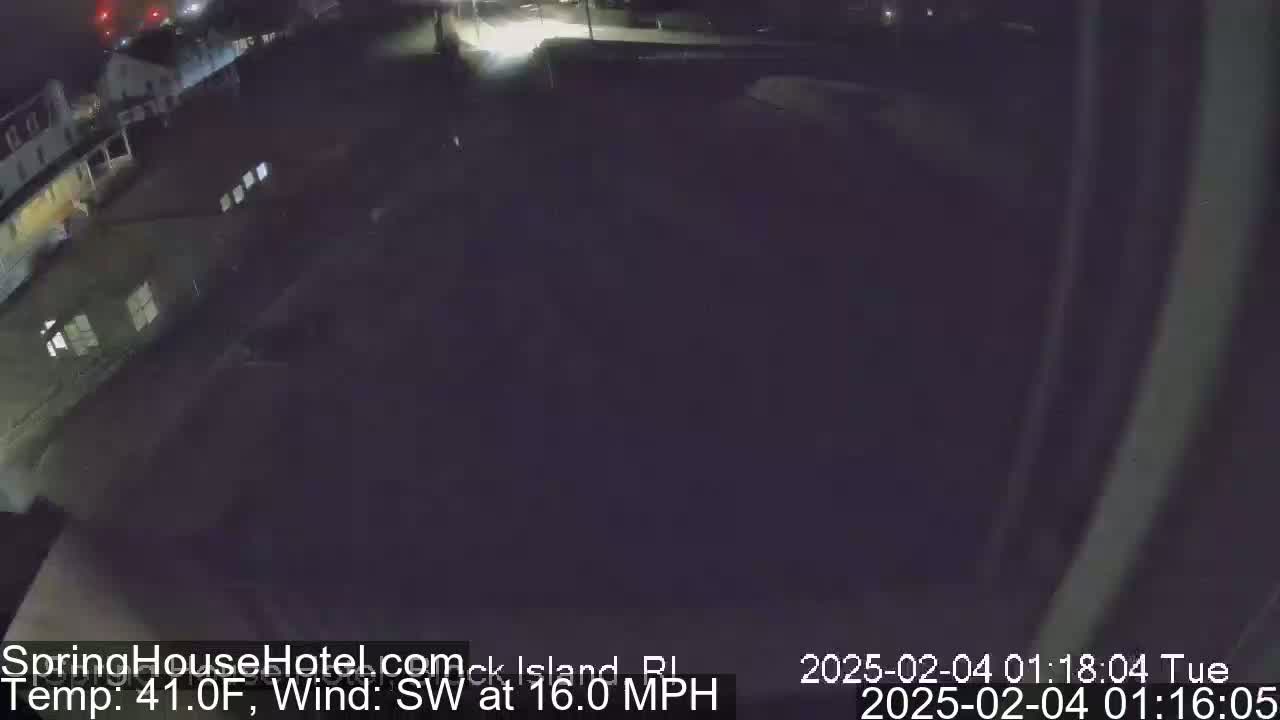 A nighttime, high-angle, long shot of a dark, possibly residential area with some buildings and a road under a dark sky with a southwest wind at 16 mph and a temperature of 41°F.
