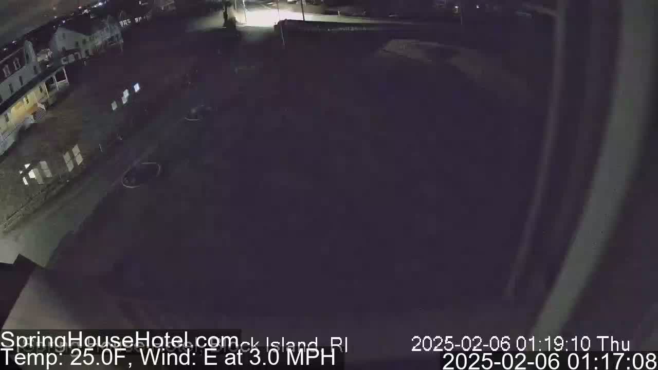 A nighttime, overhead view of a mostly empty parking lot next to a building, with a 25°F temperature and an easterly wind at 3 mph.