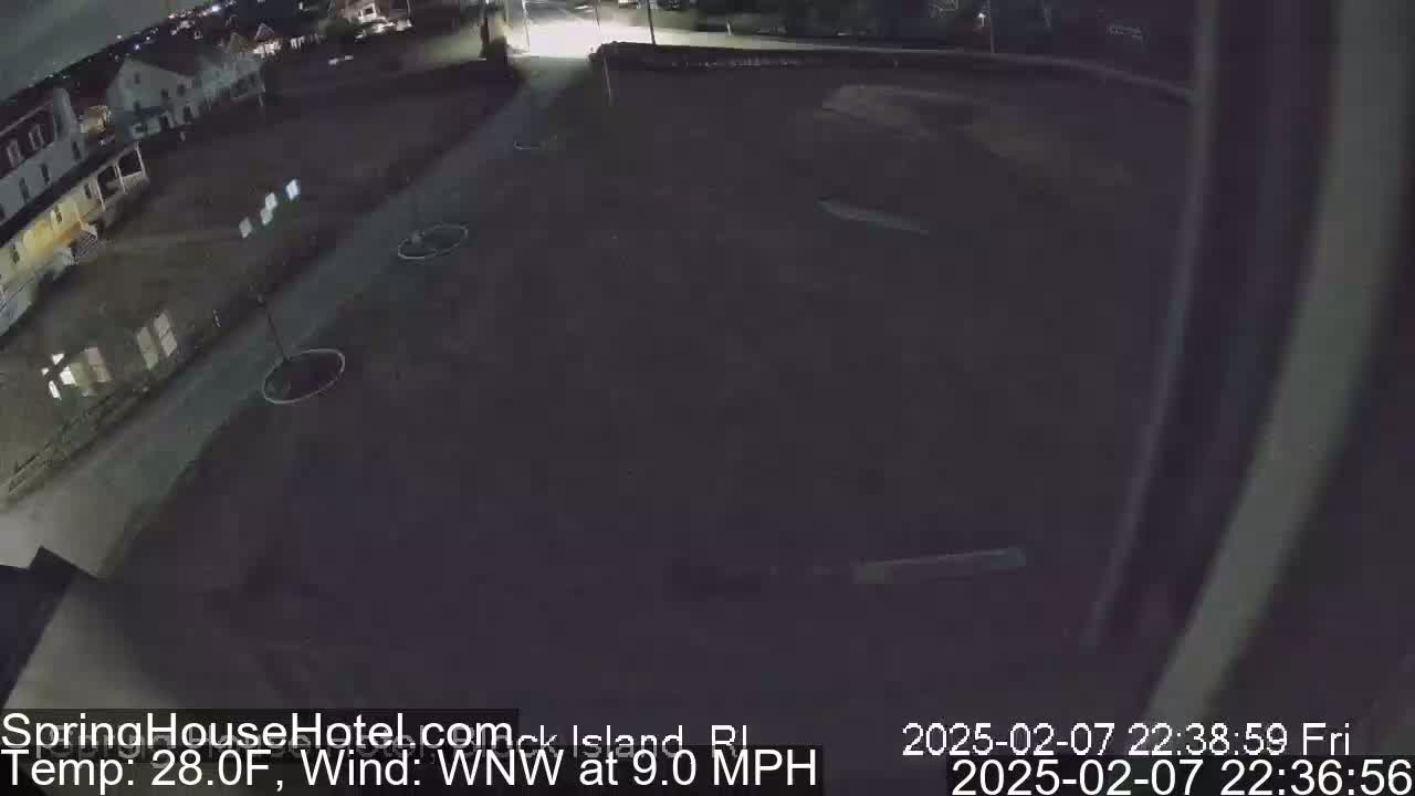 A nighttime, overhead view of a dark parking lot and street next to a building, with a 28°F temperature and a 9 mph wind from the west-northwest.
