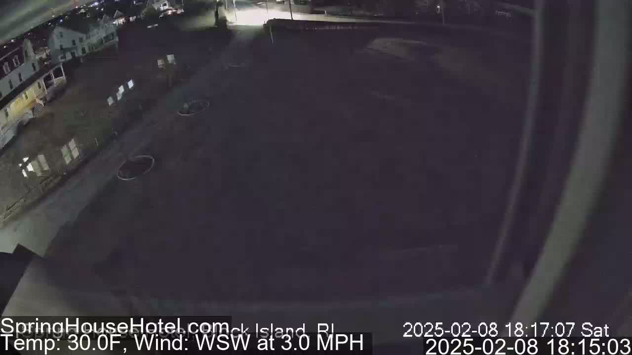 A nighttime, high-angle view of a dark, empty parking lot and a building, with a temperature of 30°F and a wind from the west-southwest at 3.0 mph.
