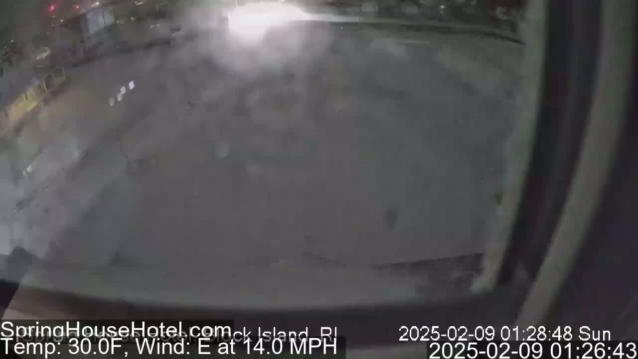 A nighttime, snow-covered parking lot is seen with a strong east wind blowing at 14 mph and a temperature of 30 degrees Fahrenheit.