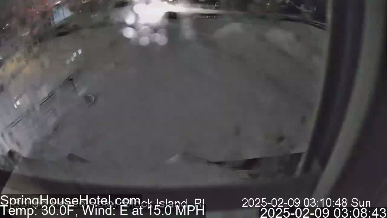 A blurry, nighttime view of a mostly empty parking lot with a 30°F temperature and 15 mph east wind.