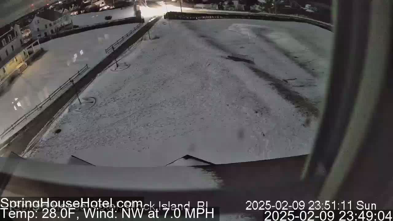 A snow-covered ground with a building in the background, under nighttime conditions with a northwest wind at 7.0 mph and a temperature of 28 degrees Fahrenheit.