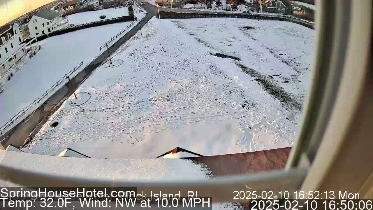 A snow-covered ground with footprints and a building partially visible in the background, under a partly sunny sky with a northwest wind at 10 mph and a temperature of 32 degrees Fahrenheit.
