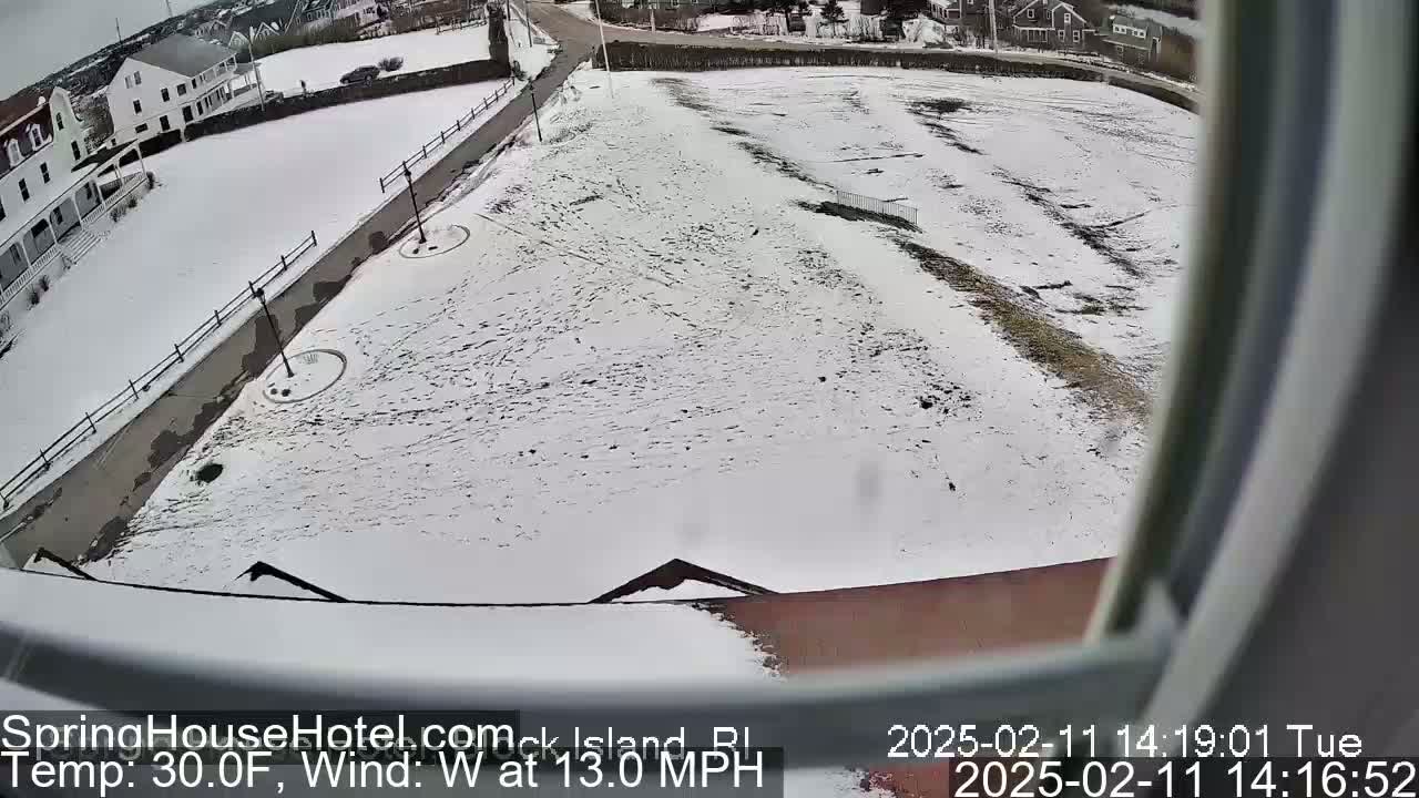 A snow-covered ground view from an elevated position shows a building, a roadway, and some sparsely vegetated areas with a west wind blowing at 13 mph and a temperature of 30°F.